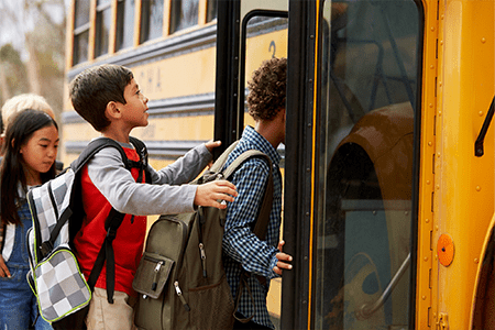 Elementary school kids climbing on to a school bus